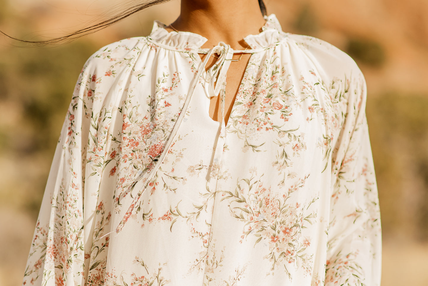 Close up details of cream floral dress, a V-neck, neck line with neck straps. bella by grace co