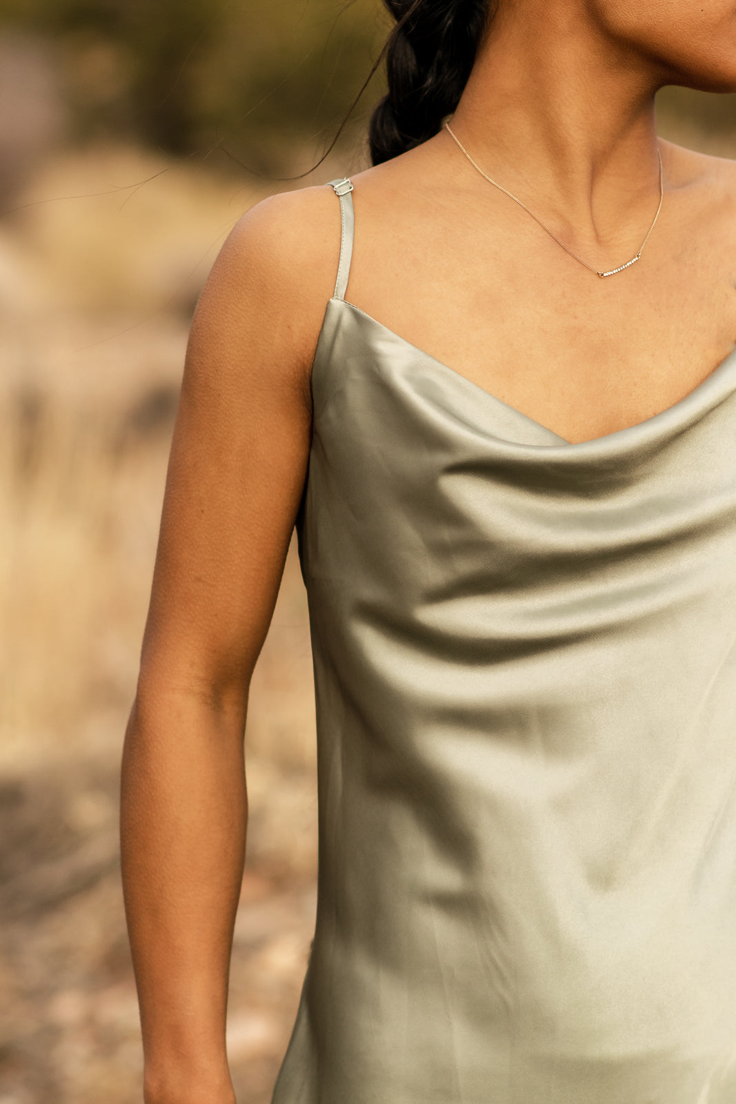 bella by grace co. Close up details of satin green slip dress with draping neckline.